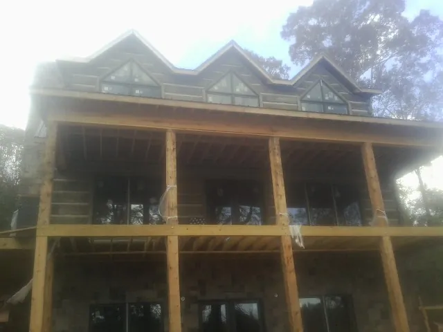 Dormers and porch framing on a large log home under construction — Roof Coating work by our crew in Donnellson