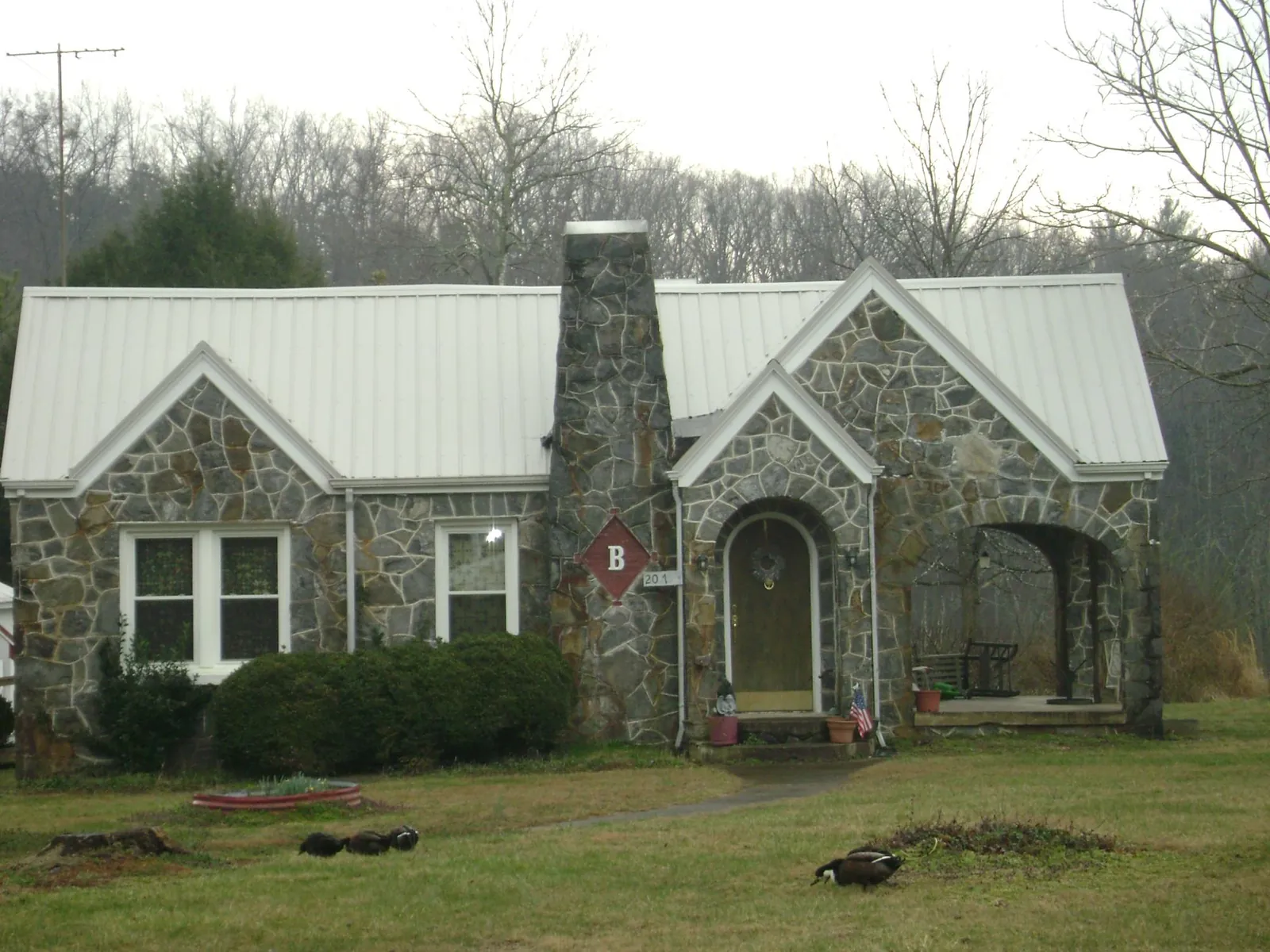 White metal roof on a stone cottage with steep gables in Donnellson