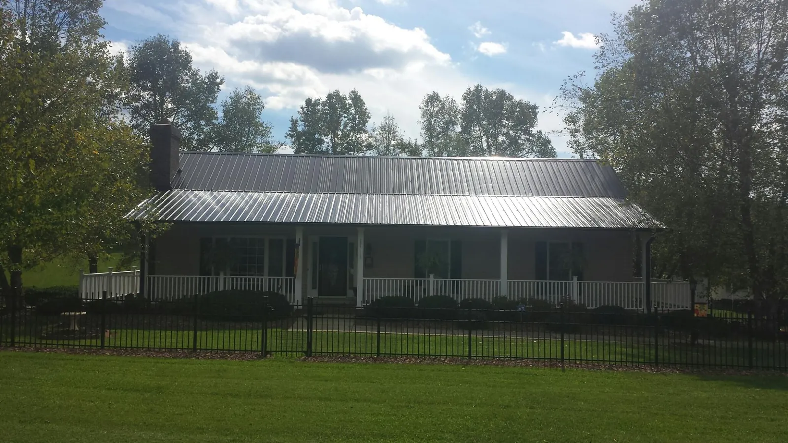 Gray metal roof on a brick ranch with a full width front porch — Gutter Guard Installation work by our crew in Donnellson