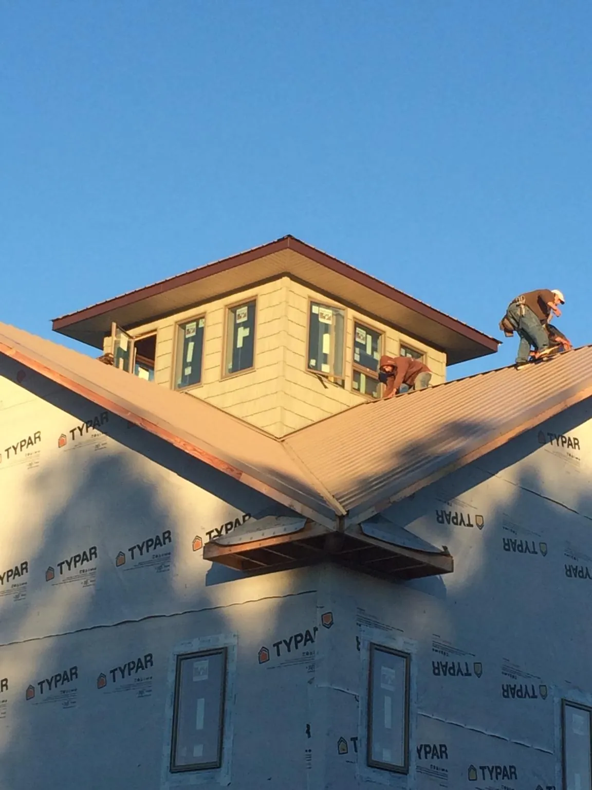 Roofers working around a rooftop cupola on a new metal roof at sunset — Roof Waterproofing in Donnellson by Roofing Brothers